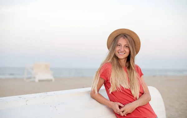 Beautiful woman with long hair wear straw hat on the beach near wooden boat. — Stock Photo, Image