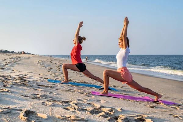 Tinere care practică yoga pe plajă. Fetele frumoase practicând yoga la malul mării . — Fotografie, imagine de stoc