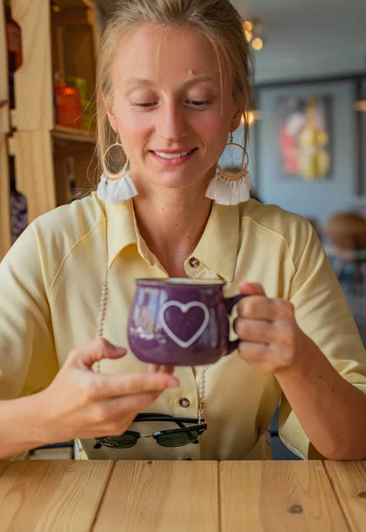 Hermosa mujer sentada en un café con una taza de café. Atractiva joven mujer está tomando café o capuchino — Foto de Stock