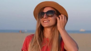 Yavaş çekimde gün batımında sahilde tatil keyfi gülümseyen mutlu kadın Portresi