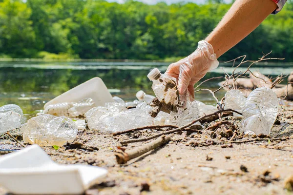 川の近くでゴミを掃除するボランティア。湖でボトルのプラスチックを拾う女性, 汚染と環境. — ストック写真