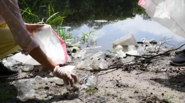 Gönüllüler nehrin yakınında çöp temizliyor. Kadınlar gölde bir şişe Plastik topluyor. Çevre kirliliği. Ekolojik sorun