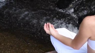 Genç kadın yoga ve meditasyon Lotus oturan şelale, kamera hamle soldan sağa yavaş hareket içinde poz çalışıyor