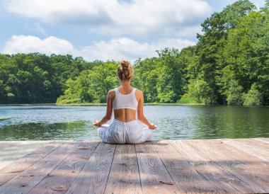 Çekici kadın yoga ve meditasyon, Lotus oturan sabah göl yakınında poz çalışıyor.