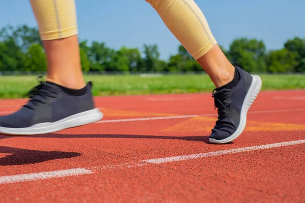 Primer plano los pies de la mujer en la pista, corredor en el carril de carrera — Foto de Stock