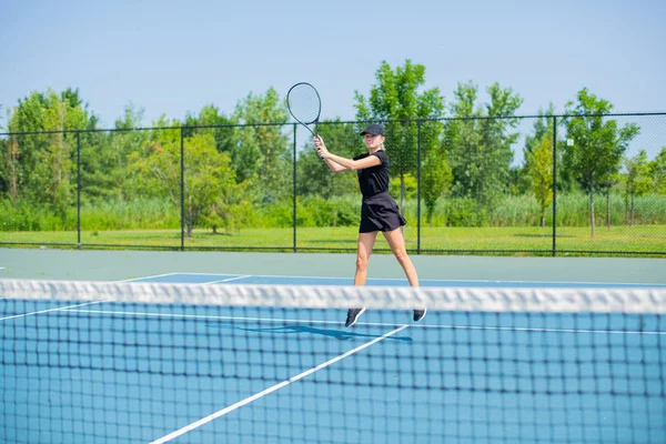 Молодая спортсменка играет в теннис на синем теннисном корте — стоковое фото