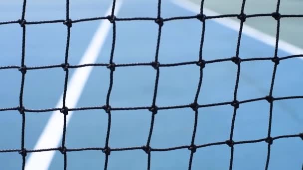 黄色いテニスボールが青いコートでネットに当たった テニスネットのクローズアップ — ストック動画