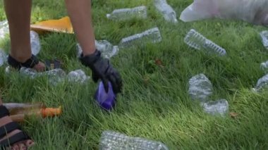 Gönüllüler parkta çöp leri temizliyor. İnsanlar çimenlerin üzerinde şişe plastik topluyorlar. Çevre kirliliği. Ekolojik sorun.