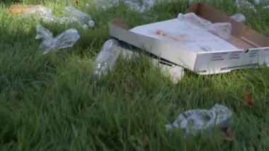 Gönüllüler parkta çöp leri temizliyor. İnsanlar çimenlerin üzerinde şişe plastik topluyorlar. Çevre kirliliği. 