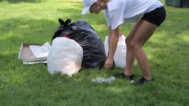 Wolontariusze Czyszczą Śmieci Parku Dziewczyna Zbierając Plastikową Butelkę Trawie Umieszcza — Wideo stockowe