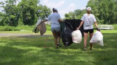 Gönüllüler parkta çöp leri temizliyor. Çöp dolu plastik torbaları olan insanlar. Çevre kirliliği. 