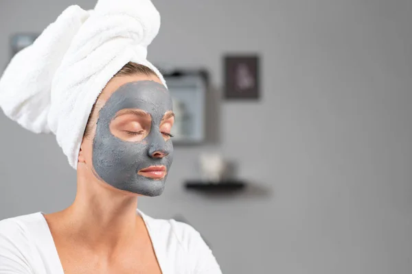 Красивая женщина надевает маску из глины для лица. Косметические процедуры и уход за кожей — стоковое фото