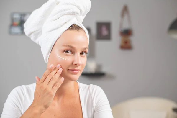 Happy young woman applying cream to her face. Woman face skin care. — Stock Photo, Image