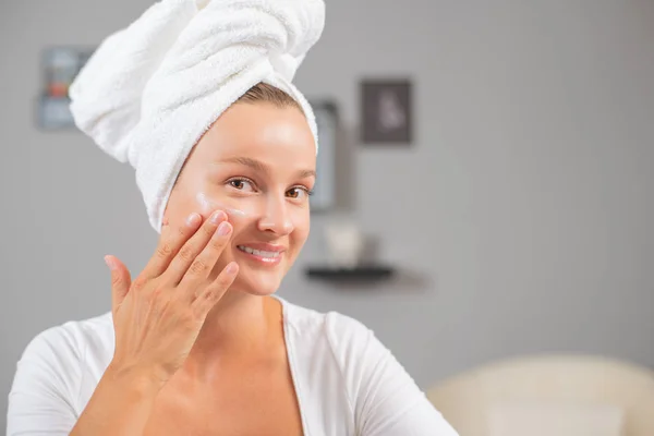 Happy young woman applying cream to her face. Woman face skin care. — Stock Photo, Image