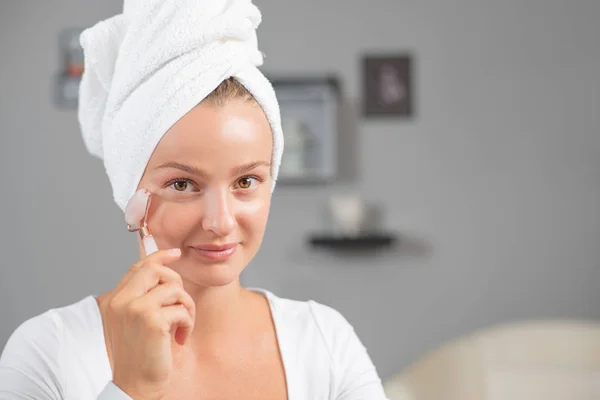 Face massage. Beautiful woman is getting massage face using jade facial roller for skin care — Stock Photo, Image