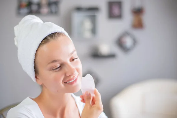 Massagem facial. Mulher bonita está recebendo rosto de massagem usando pedra de jade para cuidados com a pele — Fotografia de Stock