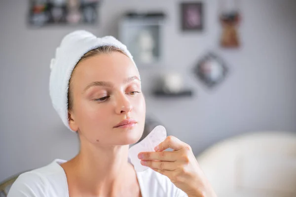 Masaje facial. Hermosa mujer está recibiendo masaje cara usando piedra de jade para el cuidado de la piel — Foto de Stock