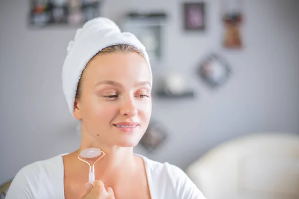 Face massage. Beautiful woman is getting massage face using jade facial roller for skin care — Stock Photo, Image