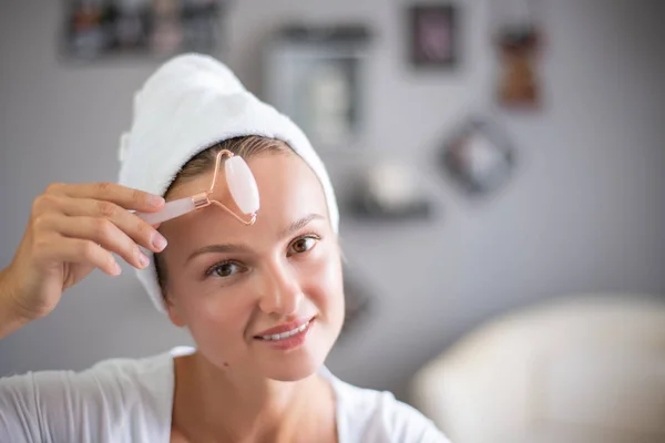 Face massage. Beautiful woman is getting massage face using jade facial roller for skin care — Stock Photo, Image