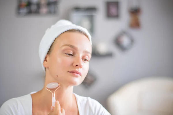 Face massage. Beautiful woman is getting massage face using jade facial roller for skin care — Stock Photo, Image