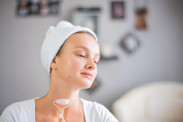 Face massage. Beautiful woman is getting massage face using jade facial roller for skin care — Stock Image Face massage. Beautiful woman is getting massage face using jade facial roller for skin care Stock Photo
