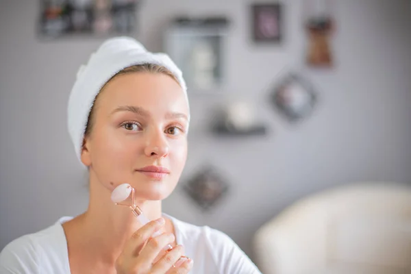 Face massage. Beautiful woman is getting massage face using jade facial roller for skin care — Stock Image Face massage. Beautiful woman is getting massage face using jade facial roller for skin care Stock Photo