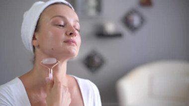 Mükemmel pürüzsüz sağlıklı bir cilt ile güzel kadın Portresi yeşim yüz rulo kullanarak masaj boyun alıyor. Yüz masajı.