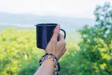 Bir dağ manzara arka planda bir kupa ile El.