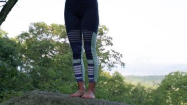 Genç kadın yavaş çekimde bir dağın tepesinde güzel egzotik bir yerde yoga yapıyor. Yoga ve meditasyon.