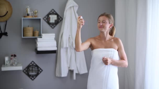 スキンケア シャワーの後にタオルに包まれた美しい女性は 彼女の首に香水を塗っています — ストック動画