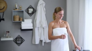 Vücut bakımı. Duştan sonra havluya sarılmış güzel kadın antiperspirant kullanıyor.