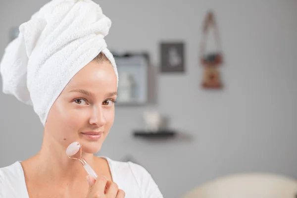 Face massage. Beautiful woman is getting massage face using jade facial roller for skin care — Stock Photo, Image