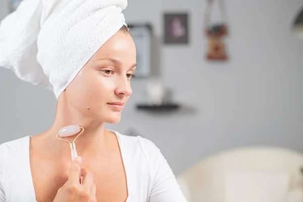 Masaje facial. Hermosa mujer está recibiendo cara de masaje utilizando rodillo facial de jade para el cuidado de la piel — Foto de Stock