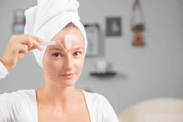 Face massage. Beautiful woman is getting massage face using jade facial roller for skin care — Stock Image Face massage. Beautiful woman is getting massage face using jade facial roller for skin care Stock Photo