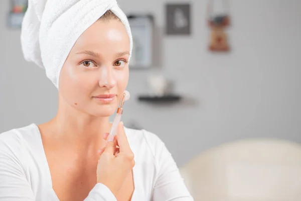 Masaje facial. Hermosa mujer está recibiendo cara de masaje utilizando rodillo facial de jade para el cuidado de la piel —  Fotos de Stock