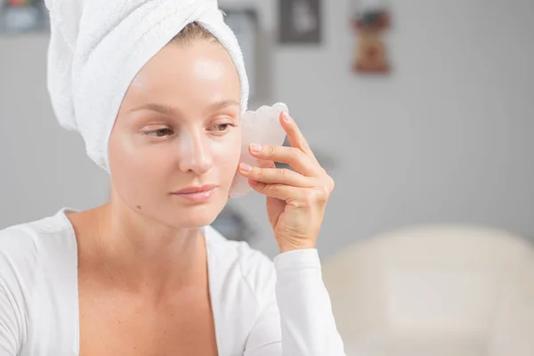 Massagem facial. Mulher bonita está recebendo rosto de massagem usando pedra de jade para cuidados com a pele — Fotografia de Stock