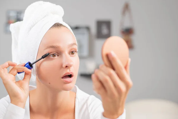 Maquillaje. Hermosa mujer está aplicando rímel en los ojos . — Foto de Stock