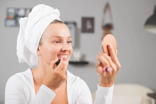 Mujer está aplicando lápiz labial rojo en sus labios — Foto de Stock