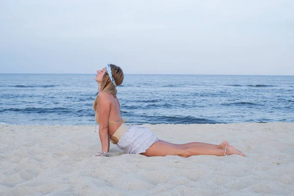 O tânără practică yoga pe plajă. Cobra pozează — Fotografie, imagine de stoc