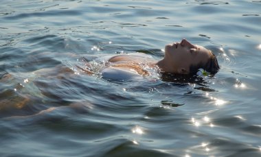 Sahil beldesinde dinleniyorum. Güzel kadın denizde geri yüzüyor.