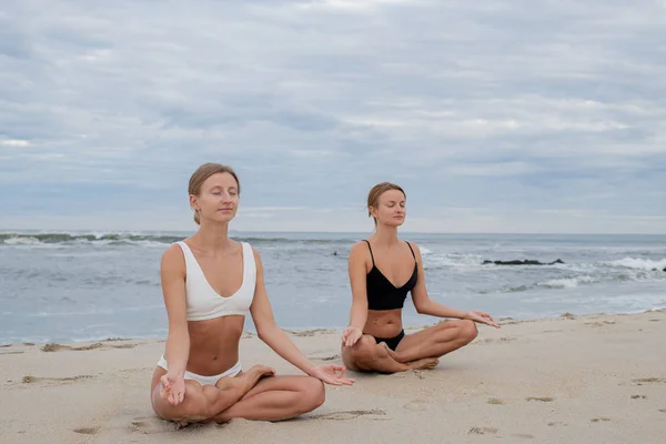 年轻女子在海滩上用莲花姿势练习瑜伽 — 图库照片