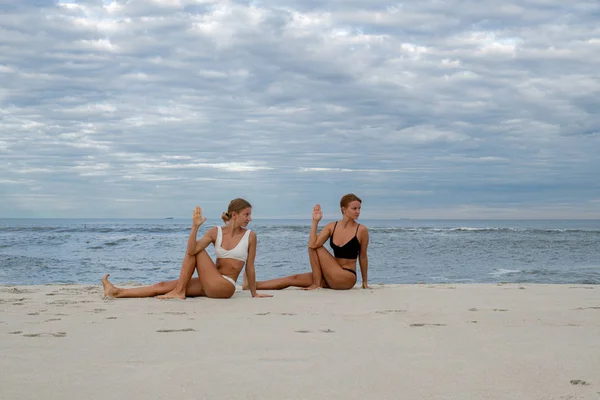 Молодые женщины практикуют йогу на пляже — стоковое фото