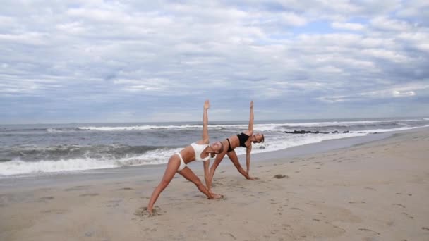 年轻女性在沙滩上慢动作练习瑜伽 美丽的女孩在海边做瑜伽 — 图库视频影像