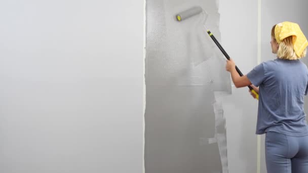 女人用滚筒装饰墙上的新公寓 漂亮的姑娘在公寓里修整 — 图库视频影像