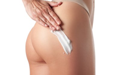 Vücut bakımı. Bacaklarına ve kalçalarına krem süren bir kadın..