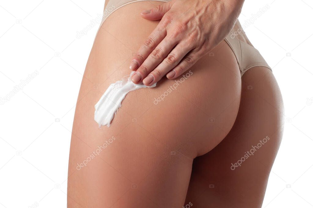Body care. Woman applying cream on legs and buttocks.