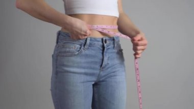 Mavi kotlu zayıf kadın kilo verdikten sonra mükemmel belini ölçüyor. Kadın kilo verdiğini gösteriyor..