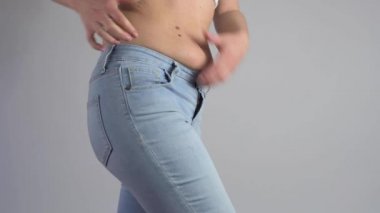 Şişman bir kadının karnına yakın çekim. Kadın aşırı kilolu, karnına yağ sıkıyor.