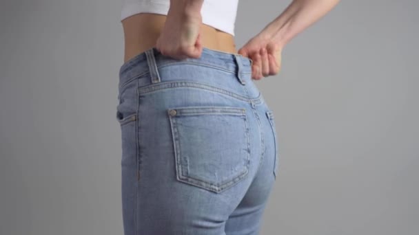 Žena se obléká do džín a zapínání zip pak ukazuje perfektní pas po úspěšné zhubnutí.