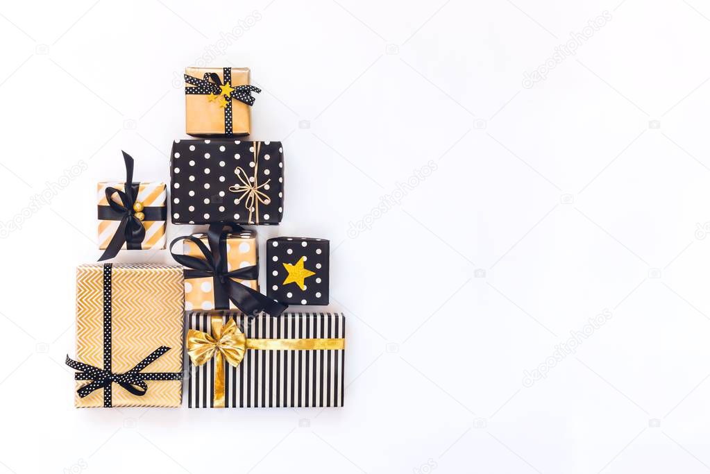 Top view of gift boxes in various black, white and golden designs arranged in triangular shape like Christmas tree or birthday cake. A concept of Christmas, New Year, birthday celebration event. Flat lay, copy space.